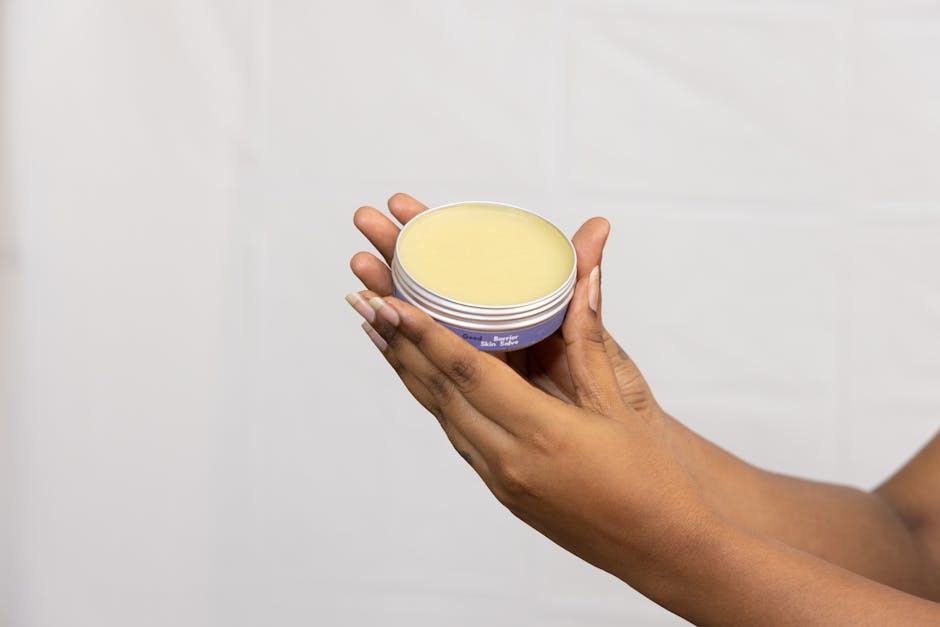 A close-up of hands holding a jar of moisturizing cream against a neutral backdrop, emphasizing skincare