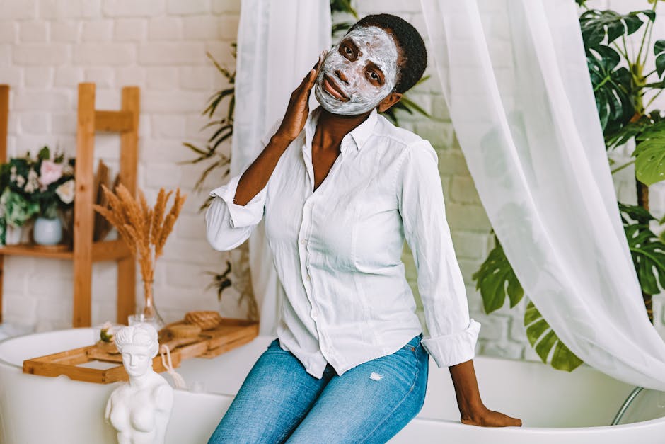 A woman enjoying a skincare routine with a clay face mask, seated indoors with a serene backdrop.