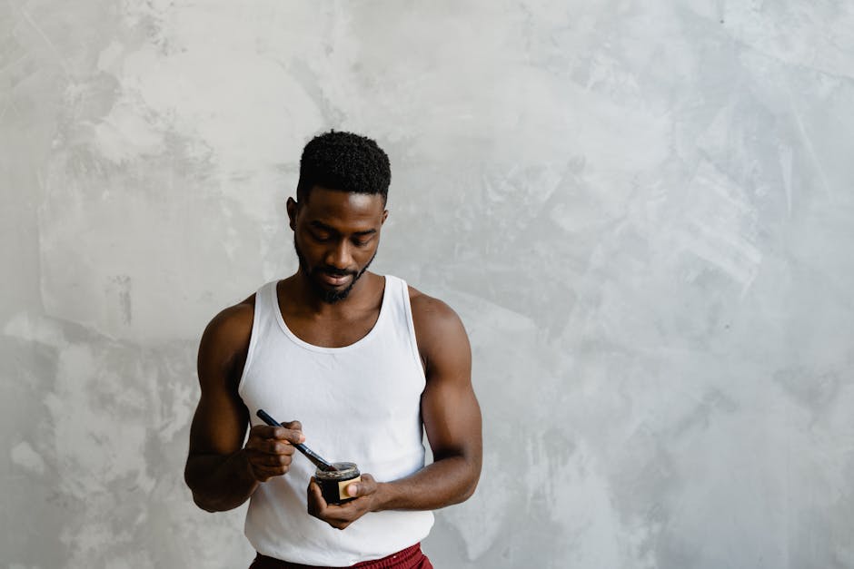 A man in a self-care routine applies a facial mask with a brush, embracing skincare