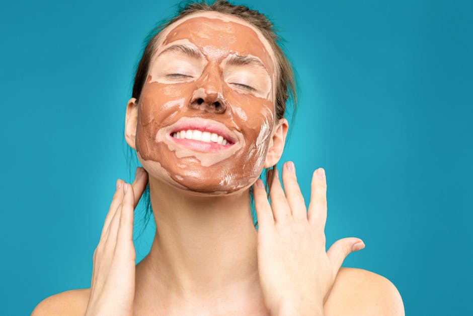 Close-up of a smiling woman with a clay facial mask, conveying relaxation and skincare routine