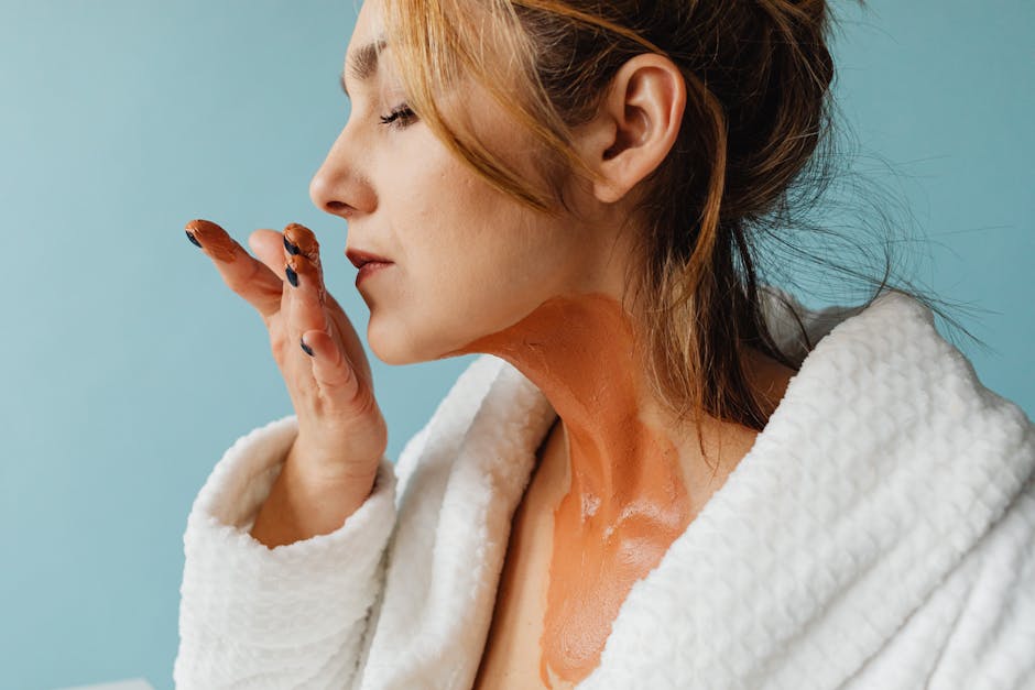 Woman in bathrobe applying face mask